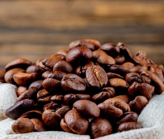 side view of brown coffee beans in a sack on rustic background